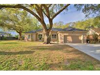 Charming single-story home with tan exterior, mature trees, and well-manicured lawn at 1 Lake Eloise Ln, Winter Haven, FL 33884