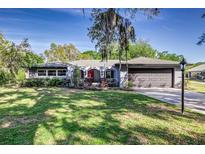Charming one-story home with a well-manicured lawn, mature trees, and a two-car garage at 115 W Christina Blvd, Lakeland, FL 33813