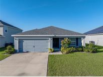 Charming single-story home with a gray exterior, well-manicured lawn, and attached two-car garage at 236 Talladega Ln, Polk City, FL 33868