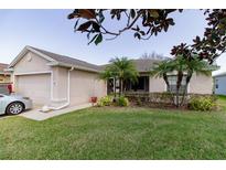 Charming home exterior featuring a well-manicured lawn, palm trees, and an attached garage at 4427 Whistlewood Cir, Lakeland, FL 33811