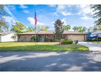 Charming single-story brick home featuring an American flag, well-manicured lawn, and an attached two-car garage at 1311 Glengreen Ln, Lakeland, FL 33813