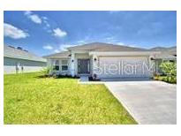 Charming single-story home with a well-manicured lawn and a long driveway leading to an attached garage at 1588 Leamington Ln, Winter Haven, FL 33884