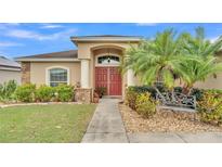 Charming home featuring a red double door entry, lush landscaping, stone accents and a decorative bench at 2030 Country Manor St, Bartow, FL 33830