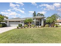 Charming single-story home featuring a manicured lawn, palm trees, and a neatly landscaped garden at 3001 Plantation Rd, Winter Haven, FL 33884