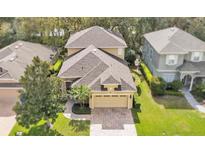 Aerial view of a two-story home with a brick driveway and a well-maintained lawn with mature trees at 4759 Lathloa Loop, Lakeland, FL 33811