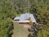 An aerial view of a house with a metal roof nestled among trees, showcasing its secluded and natural setting at 4410 Rushing Rd, Lakeland, FL 33810