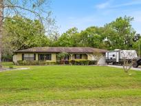 Charming single-story home with lush green lawn, mature trees, and covered entrance at 6940 Newman E Cir, Lakeland, FL 33811