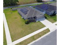 Charming single-story home featuring solar panels, a well-manicured lawn, and a convenient two-car garage at 937 Montgomery Ln, Polk City, FL 33868