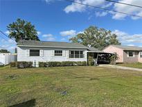 Charming single-story home with well-maintained lawn, carport and mature trees under a blue sky at 129 Nw 10Th Dr, Mulberry, FL 33860