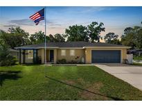 Charming single-story home with well-manicured lawn and attached two car garage and US flag at 1404 Maple St, Lakeland, FL 33810