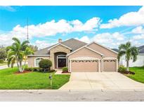Charming home featuring a stone accent façade, a three-car garage, lush lawn, and mature palm trees at 2814 Sheldon St, Lakeland, FL 33813