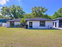 Charming single-story home with a well-manicured lawn and lush landscaping at 2821 Grapefruit Dr, Auburndale, FL 33823