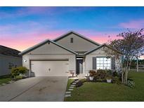 Charming single-story home with a two-car garage, stone-lined walkway, and manicured landscaping at 301 St Georges Cir, Eagle Lake, FL 33839