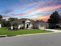 Beautiful single-story home featuring manicured lawn, mature trees, and attached two-car garage at 6472 Evergreen Park Dr, Lakeland, FL 33813