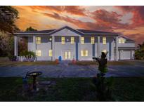 Stately two-story home with white siding, columns, and a manicured front lawn at sunset at 2653 State Road 557, Lake Alfred, FL 33850