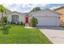 Charming single-story home with a well-manicured lawn and a vibrant red front door at 307 Balmoral Ct, Davenport, FL 33896