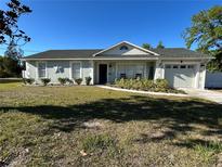 Charming single story home with a well-manicured lawn, decorative shutters, and an attached garage on a sunny day at 4215 Sabal Palm Dr, Mulberry, FL 33860