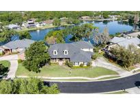 Stunning lakefront home featuring a lush green lawn, mature trees, and a circular driveway at 5789 Lake Victoria Dr, Lakeland, FL 33813