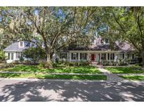 Charming home with lush front yard, mature trees, and a welcoming red front door at 6704 Crescent Lake Dr, Lakeland, FL 33813
