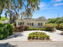 Charming single-story home featuring a circular driveway, mature landscaping, and moss-draped trees on a sunny day at 1390 S 1St Ave, Bartow, FL 33830