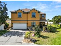 Two-story home featuring a two-car garage, and a well-manicured lawn with vibrant landscaping at 181 James Cir, Lake Alfred, FL 33850