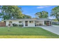 Charming single-story home with a well-manicured lawn and a covered carport on a sunny day at 5527 Flamingo Ave, Lakeland, FL 33809