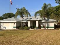 Inviting single-story home featuring a lush front yard, palm trees, and a charming entrance with an American flag at 871 Thornburg Rd, Babson Park, FL 33827