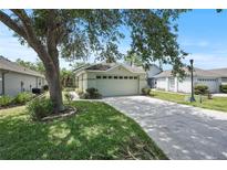 Charming home featuring an attached garage, lush green lawn, and mature trees providing shade on a sunny day at 4139 Cobblestone Dr, Lakeland, FL 33813