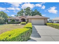 Charming brick home with a manicured lawn, mature landscaping, and a two-car garage at 7230 Hileman W Dr, Lakeland, FL 33810