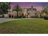 Stunning two-story stucco home featuring an arched entry, lush lawn, mature landscaping, and detached garage at 845 E Edgewood Dr, Lakeland, FL 33803