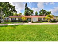 Charming single-story home with a red roof, lush landscaping, and a brick driveway at 1407 Easton Dr, Lakeland, FL 33803