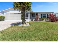 Charming single-story home featuring a well-manicured lawn, mature palm tree, and an attached screened garage at 2085 Long Boat Dr, Lakeland, FL 33810