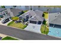 Beautiful home showcasing a well-manicured lawn, gray color palette and a spacious driveway with a unique palm tree design at 2129 Landrea Loop, The Villages, FL 32163