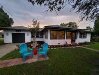 Charming single-story home with blue Adirondack chairs on a brick patio and well-manicured lawn at 308 Ne 10Th Ave, Mulberry, FL 33860
