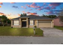 Charming single-story home featuring a well-manicured lawn and a two-car garage, set against a colorful sky at 3112 Otto Dr, Lakeland, FL 33812