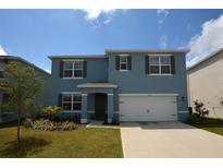 Charming two-story home features a blue exterior, well-maintained lawn, and a two-car garage at 3882 Resting Robin Ave, Bartow, FL 33830