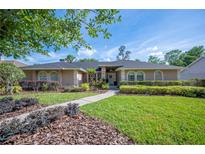 Charming single story home featuring manicured landscaping, green lawn, and a welcoming front entrance at 6911 Wildberry Ln, Lakeland, FL 33813