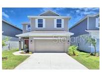 Charming two-story home with a well-manicured lawn, attached two-car garage, and neutral-colored exterior at 2303 Brassie Ct, Winter Haven, FL 33884