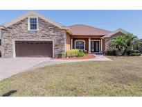 Beautiful single-story home boasts a stone facade, brown siding, well-manicured lawn, and a two-car garage at 5612 Vintage View Blvd, Lakeland, FL 33812