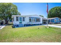 Charming single-story home with blue and white trim, lush lawn, and an American flag at 1506 Longbow Dr, Lakeland, FL 33810