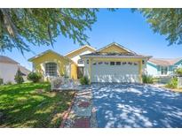 Charming single-story home with a well-manicured lawn, mature tree, and a two-car garage at 217 Dillon Way, Davenport, FL 33897