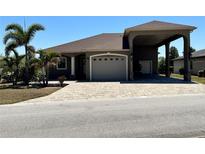Charming single-story home with a paver driveway, covered portico, and lush landscaping at 564 Meandering Way, Polk City, FL 33868
