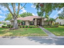 Charming single-story home featuring mature trees, lush landscaping, and a welcoming front entrance at 1104 Kells Ct, Lakeland, FL 33813