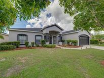 Charming single Gathering home boasts professional landscaping, healthy green lawn, and a two car garage at 2033 Normandy Heights Dr, Winter Haven, FL 33880