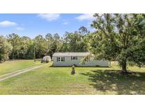 Charming single-story home with lush green lawn and mature trees offering a serene and private setting at 7011 Tall Pine Rd, Polk City, FL 33868