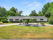 Charming single-story home featuring a well-manicured lawn and mature trees creating a serene and private setting at 1205 Rolling Woods Ln, Lakeland, FL 33813