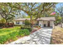 Charming home with well-manicured front lawn, mature trees, and an American flag at 209 S Hydrangea Ave, Polk City, FL 33868