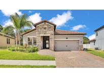 Charming home featuring a stone facade, clay tile roof, and a well-manicured lawn at 2277 Bella Luna Cir, Lakeland, FL 33810