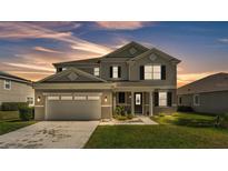 Charming exterior view of home featuring a two-car garage, well-maintained lawn, and a welcoming front porch at 2468 Winnipeg Dr, Lakeland, FL 33805