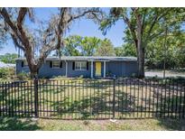 Charming single-story home features a well-manicured lawn, decorative fence, and a bright yellow front door at 3880 Cleveland Heights Blvd, Lakeland, FL 33813